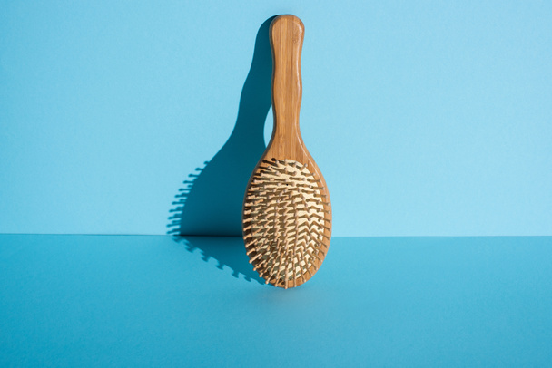 Деревянная щетка для волос на синем фоне, нулевая концепция отходов
 - Фото, изображение