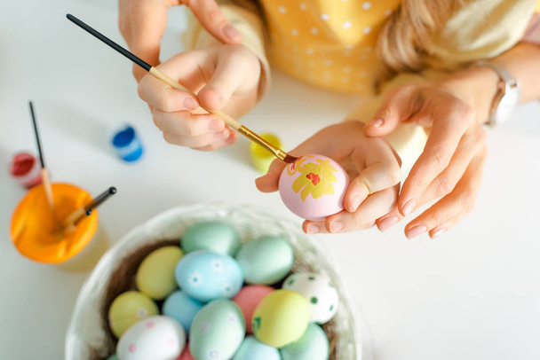 vista superior del niño pintando huevo de Pascua cerca de la madre en blanco
  - Foto, imagen