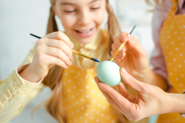 selective focus of happy daughter and mother painting easter egg  - Photo, image