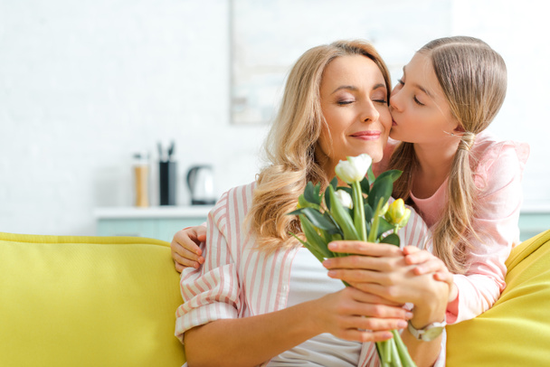 fille mignonne embrasser mère heureuse tenant bouquet de tulipes
  - Photo, image