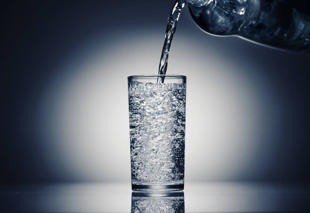 versando acqua frizzante in un bicchiere su uno sfondo blu scuro
 - Foto, immagini