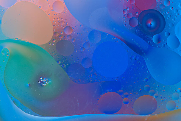 модні бульбашки та мазки олійних крапель на поверхні води на кольоровому фоні
 - Фото, зображення