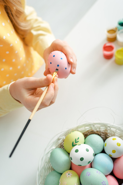 κορυφαία άποψη του παιδιού ζωγραφική πασχαλινό αυγό με πινέλο στο σπίτι - Φωτογραφία, εικόνα