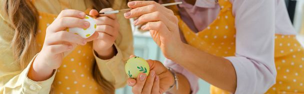panoramic shot of mother and daughter painting chicken eggs on easter  - Foto, immagini