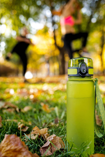 egy üveg víz a zöld füvön. szabadtéri edzést végző sportos nők - Fotó, kép
