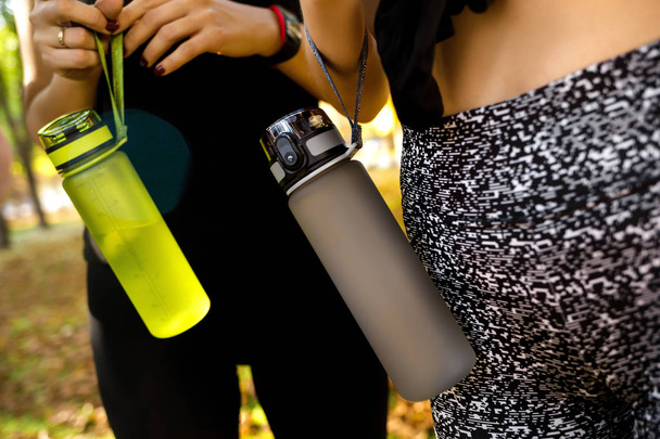sports women standing together with bottles of water after exercising - Photo, Image