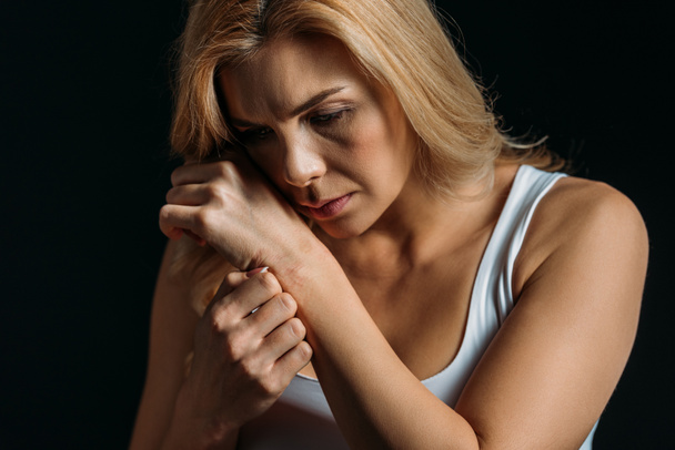 Thoughtful and upset woman with hand near face isolated on black - Valokuva, kuva