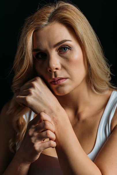 Woman touching hand and looking at camera isolated on black - Photo, image