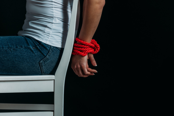 Cropped view of woman with tied hands on chair isolated on black - Foto, Bild