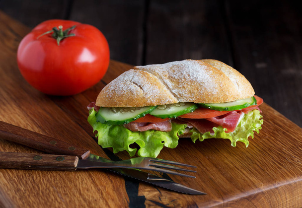 Whole sandwich on wooden board with tomato - Foto, Bild