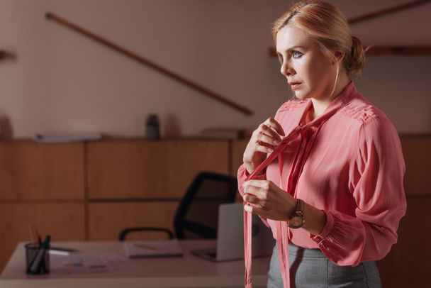 Selective focus of woman untying ribbons on blouse in office, sexual harassment concept - Foto, Bild