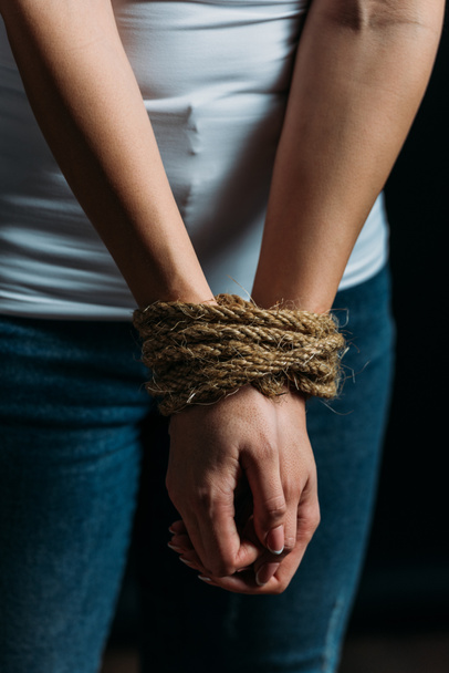 Cropped view of victim hands tied with rope isolated on black - Foto, Imagen