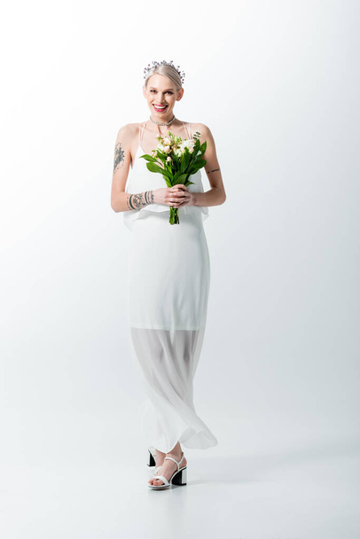 happy beautiful tattooed bride with bouquet on white - 写真・画像