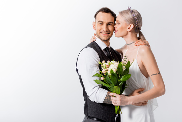 happy beautiful tattooed bride and handsome bridegroom kissing isolated on white - Foto, immagini