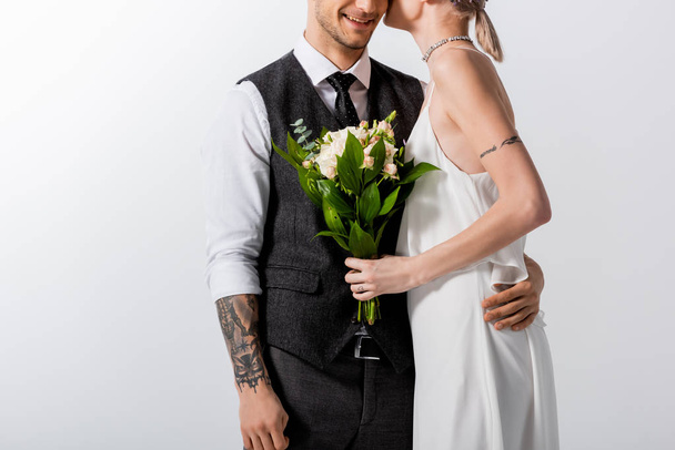 abgeschnittene Ansicht von glücklich schönen tätowierten Braut und schönen Bräutigam küssen isoliert auf weiß - Foto, Bild