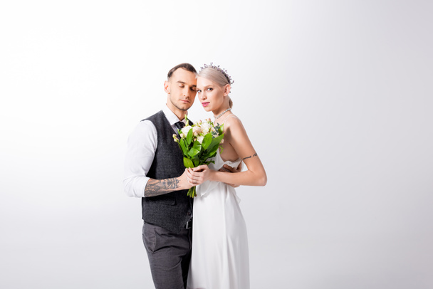 beautiful tattooed bride with bouquet and handsome bridegroom on white - 写真・画像