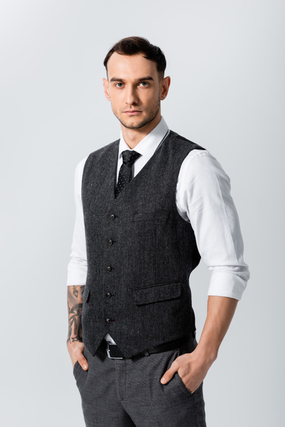 handsome tattooed elegant bridegroom with hands in pockets isolated  on grey - Foto, afbeelding