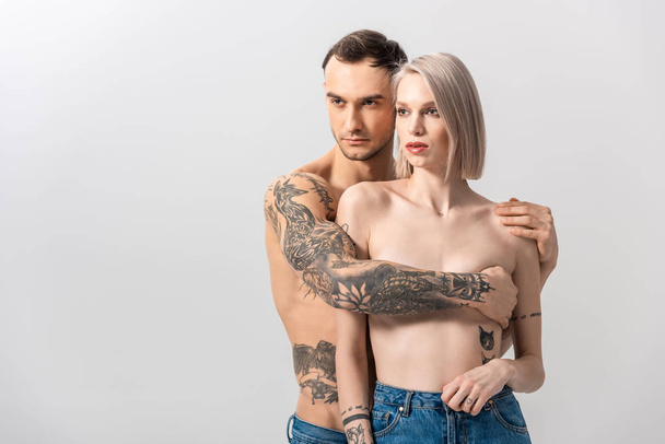 jovem sem camisa tatuado casal em jeans abraçando isolado no cinza
 - Foto, Imagem
