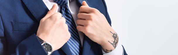 cropped view of successful tattooed businessman in blue suit with hands on blazer isolated on white, panoramic shot - Фото, зображення