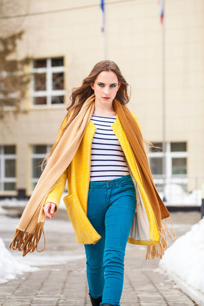 Young beautiful woman in yellow coat walking winter park - Фото, изображение