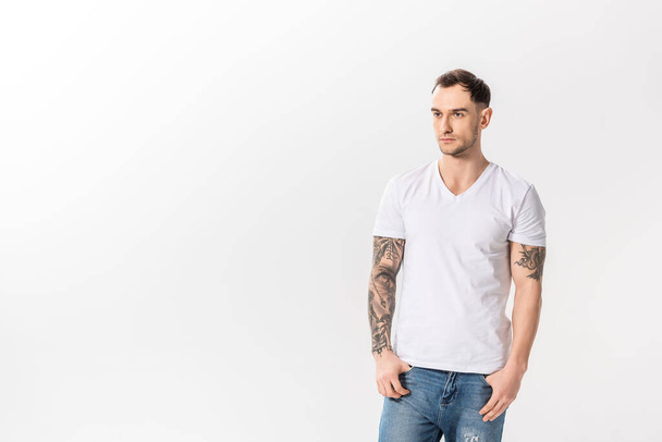 schöner junger tätowierter Mann in Jeans posiert isoliert auf weißem Grund - Foto, Bild