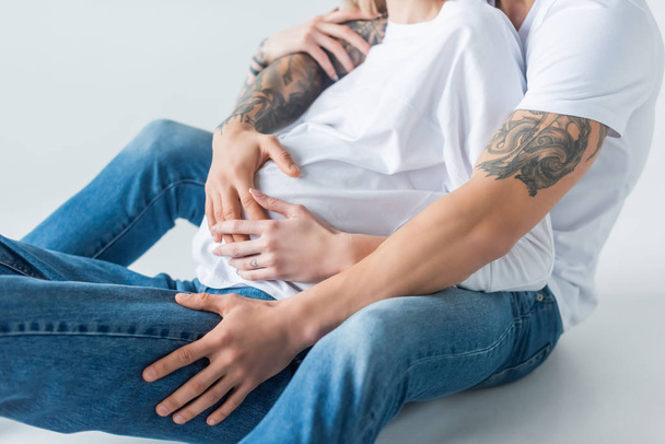 kivágott kilátás fiatal tetovált terhes nő ül közelében férj szürke - Fotó, kép