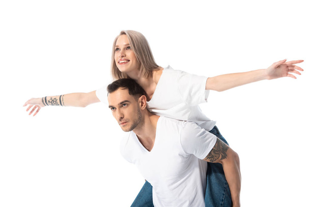 happy young tattooed couple piggybacking isolated on white - 写真・画像