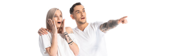 shocked young tattooed couple pointing with finger away isolated on white, panoramic shot - Zdjęcie, obraz