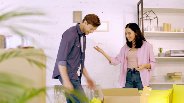 Jovem casal jogando tesoura de papel de rocha perto de pacotes em nova casa
 - Filmagem, Vídeo
