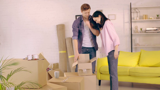 Pareja abrazándose mientras desempaca la caja en un nuevo hogar
 - Metraje, vídeo