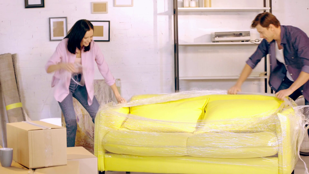 Couple joyeux déballer canapé dans une nouvelle maison
 - Séquence, vidéo