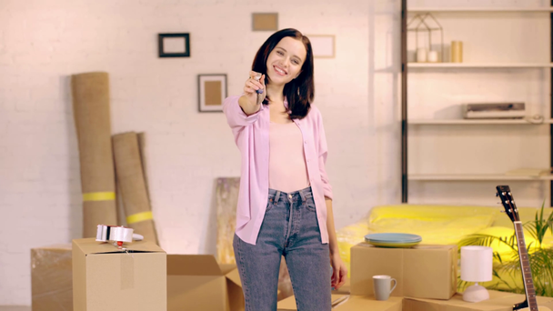 Hymyilevä nainen näyttää avaimia kameran uudessa kodissa - Materiaali, video