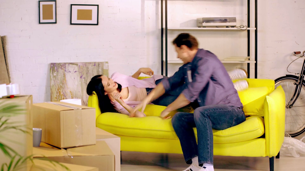 Couple fooling around on sofa near packages in new home - Video, Çekim