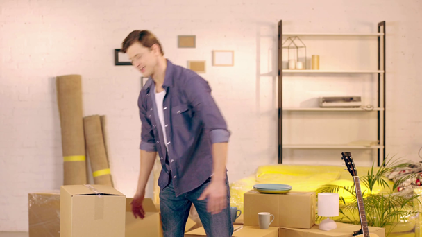 Homme souriant mettant paquet et montrant pouce dans une nouvelle maison
 - Séquence, vidéo