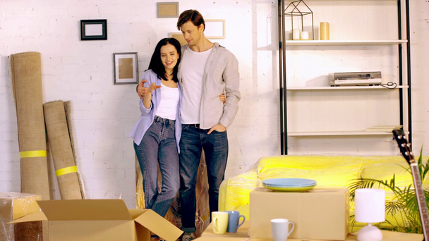 Junges Paar umarmt und redet in der Nähe von Paketen im neuen Zuhause - Filmmaterial, Video