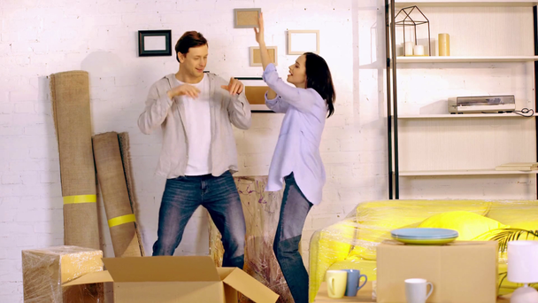 Fiatal pár, akik dobozok közelében táncolnak az új otthonban - Felvétel, videó