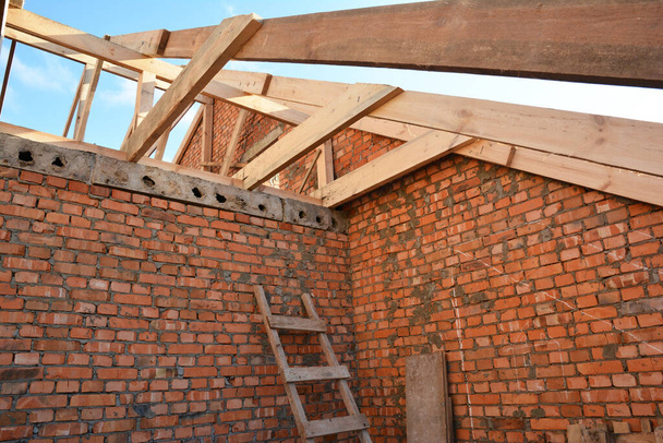 Ziegelhaus Dachgeschoss im Bau mit Rahmen aus Holzbalken, Dachstühlen, Dachüberhängen - Foto, Bild