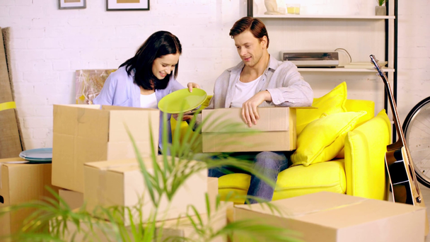 Couple packing plates in packages on couch - Footage, Video