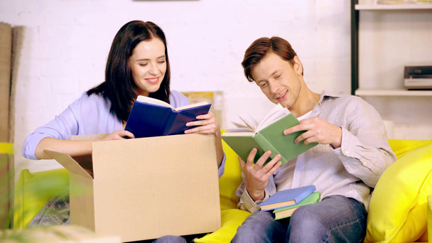 Paar lachen tijdens het uitpakken van boeken op de bank - Video
