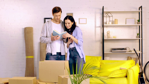 Paar liest Buch in der Nähe von Boxen im Wohnzimmer - Filmmaterial, Video