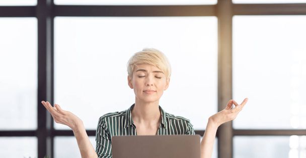 Senhora de negócios calma meditando durante o dia estressante no local de trabalho, Panorama
 - Foto, Imagem