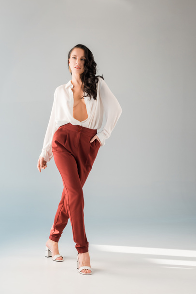 attractive and sexy woman in shirt and trousers walking on grey background  - Fotografie, Obrázek