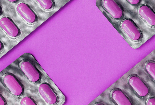 Purple tablets in a blister pack, pills in foil blister packs, medications drugs on purple surface. Medicines for various diseases. Top view - 写真・画像