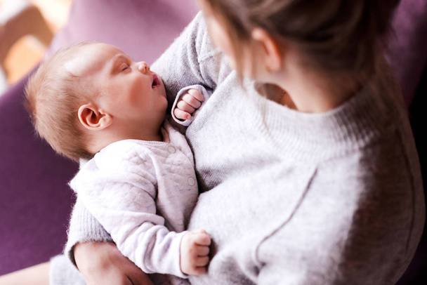 Schlafendes Baby auf den Händen der Mutter in Zimmernahaufnahme. Mutterschaft. Mutterschaft. Ansicht von oben.  - Foto, Bild