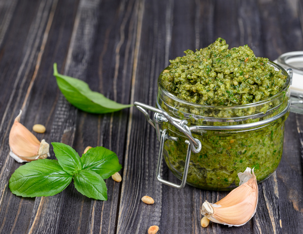 Pesto sauce in a jar with pine nuts, parmesan and garlic over da - Photo, Image