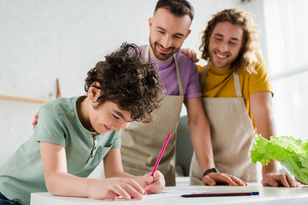 selective focus of mixed race kid drawing picture near happy homosexual parents  - Photo, Image