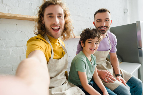 επιλεκτική εστίαση των όμορφων ομοφυλόφιλων ανδρών χαμογελώντας με χαριτωμένο παιδί μικτή φυλή  - Φωτογραφία, εικόνα
