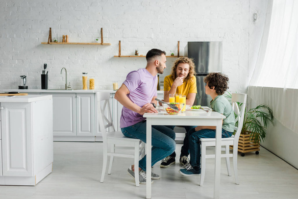 homoseksuele ouders en schattig gemengd ras zoon lunchen thuis - Foto, afbeelding
