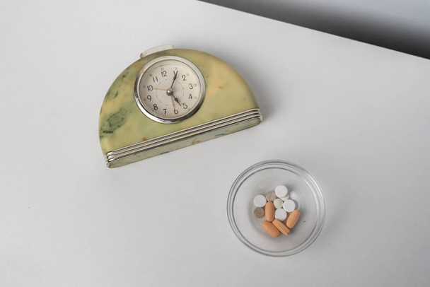 alarm clock on the shelf with the medicine pills, treatment schedule plan - Photo, image