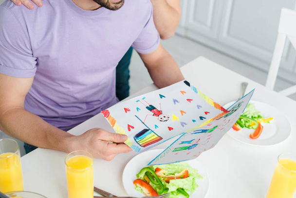 Homoseksüel erkeklerin ellerinde kağıtlarla salata ve portakal suyu bardaklarının yanına çizim yapmaları.  - Fotoğraf, Görsel
